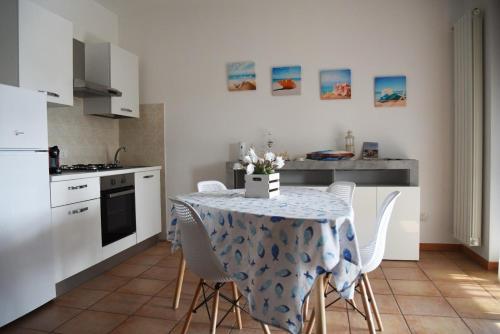 a kitchen with a table with white chairs and a kitchen with white appliances at Appartamento Lago Playa in Desenzano del Garda