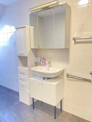 ein weißes Badezimmer mit einem Waschbecken und einem Spiegel in der Unterkunft Zentrale Wohnung l Netflix l Internet I bis 5 Gäste in Iserlohn