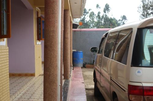a white van parked next to a building with columns at DAR Guest House in Kabarole