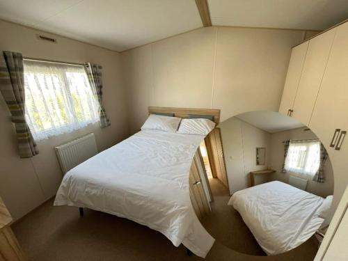 a small bedroom with two beds and a mirror at 134 HOLIDAY RESORT UNITY BREAN PASSES INCLUDED Pets stay free Max 2 pets in Brean