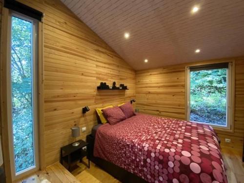 - une chambre avec un lit dans une pièce dotée de murs en bois dans l'établissement Woody Lodge - Duplex Nature Bonsoy Ardennes, à Hastière-par-delà