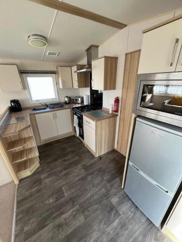 a kitchen with white cabinets and a refrigerator at Spacious accomodation 134 UNITY BEACH BREAN CENTRALLY LOCATED Sleeps 6 Pet friendly Pets stay free in Brean