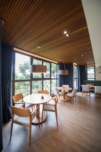 a dining room with tables and chairs and windows at Pinot Hotel in Campos do Jordão