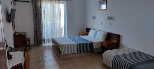 una camera d'albergo con due letti e una finestra di VENOS APARTMENTS a Marmári