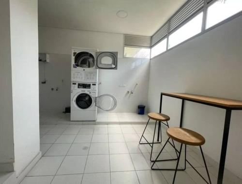 een wasruimte met een wasmachine en 2 krukken bij Montpellier Santa Marta. in Santa Marta