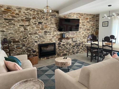 a living room with a stone wall with a fireplace at Casa da Meia Encosta in Arganil
