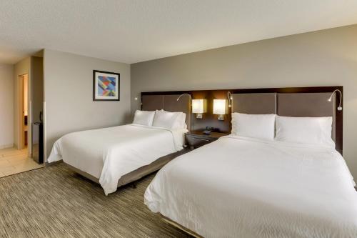 two beds in a hotel room with white sheets at Holiday Inn Express Hotel & Suites Bryan-Montpelier by IHG in Holiday City