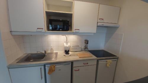 une petite cuisine avec un évier et un micro-ondes dans l'établissement Beau T2, très calme, 3*, première ligne de la Marina Canet en Roussillon, à Canet