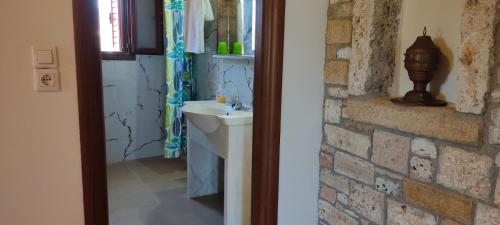 a bathroom with a sink and a brick wall at VENOS APARTMENTS in Marmari