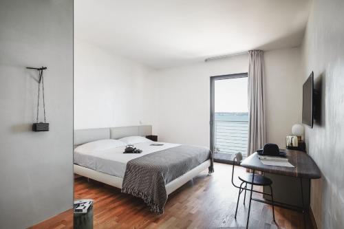 a bedroom with a bed and a desk and a window at AQVA Boutique Hotel (Adults Only) in Sirmione