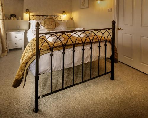 a bedroom with a bed with a wrought iron bed frame at The Green Dragon at Bedale in Bedale
