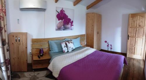 a bedroom with a bed with purple sheets and blue pillows at LA LIVADA in Valea Danului