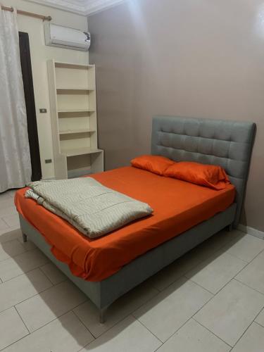a bed in a room with an orange comforter at THURIN IMO (Vauvert) in Saint-Louis