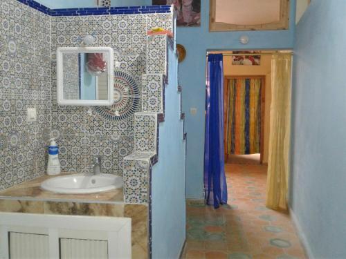 a bathroom with a sink and a mirror at Maison d hôtes Tioute Chez Abdelmajid in Tiout