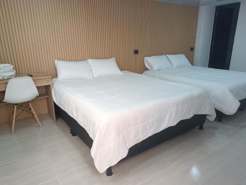two beds in a room with a desk and a chair at Hotel Cordi in Guatavita