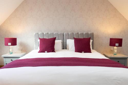 a bedroom with a large white bed with red pillows at Stornoway Bed and Breakfast in Stornoway