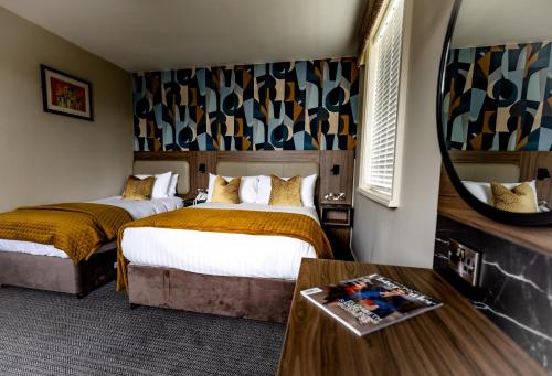 um quarto de hotel com duas camas e um espelho em Ballymac Hotel em Stonyford
