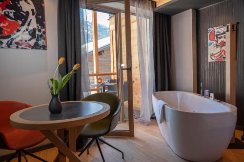 a bathroom with a tub and a table and chairs at Locanda degli Artisti Art Hotel in Canazei