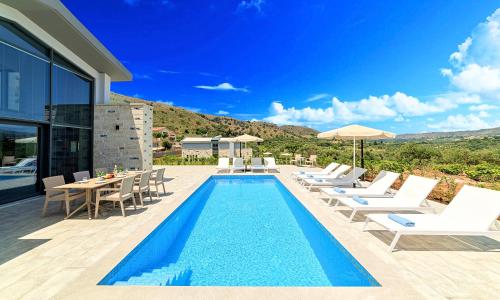 una piscina con tumbonas y una villa en Moonlights Villas Heated Pool en Georgioupoli