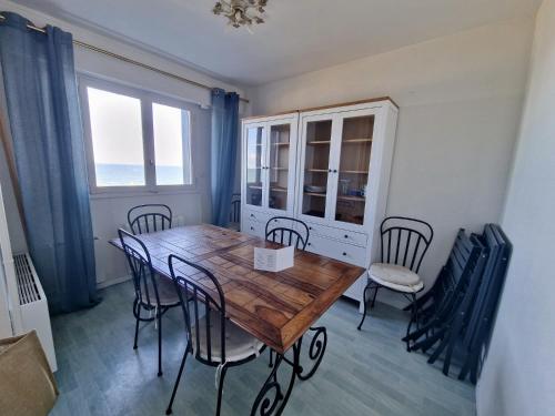 une salle à manger avec une table et des chaises en bois dans l'établissement Duplex vue sur mer, à Cabourg