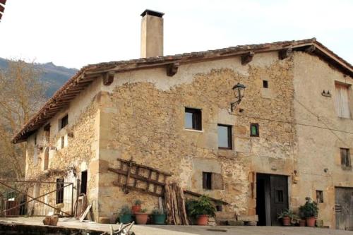 ein altes Steingebäude mit einem Schornstein darauf in der Unterkunft GOIKO ETXE Refugio Rural in Urdiáin