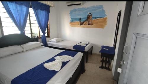 a bedroom with two beds and a painting of a beach at Hotel Kelly Mar in Tolú