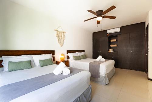 a bedroom with two beds and a ceiling fan at Via Tendenza Condos in Playa del Carmen