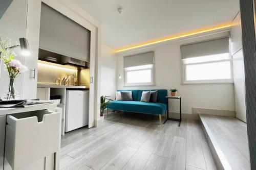 ein Wohnzimmer mit einem blauen Sofa und einer Küche in der Unterkunft Apt 09 Stylish Studio Steps from Sea & Promenade in Brighton & Hove