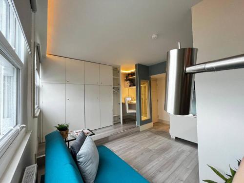 ein Wohnzimmer mit einem blauen Sofa und einer Küche in der Unterkunft Apt 09 Stylish Studio Steps from Sea & Promenade in Brighton & Hove