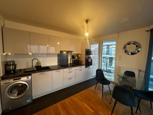 une cuisine avec un lave-linge, une table et des chaises dans l'établissement Élysée Lumière Résidence Prestige Paris-La Défense, à Colombes