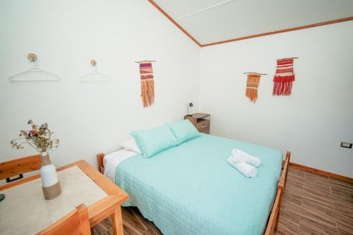 a bedroom with a blue bed and a table at Tantakuy Eco Experience Hotel in La Huaica