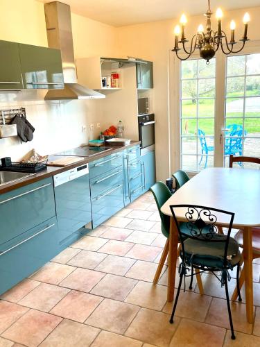 a kitchen with blue cabinets and a table and chairs at Villa sur les bords de la Seine à 1h de Paris in Moisson