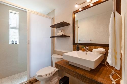 a bathroom with a sink and a toilet and a mirror at Via Tendenza Condos in Playa del Carmen