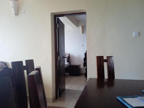 a dining room with a table and chairs and a hallway at Lagos Diani in Diani Beach