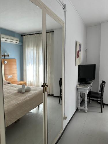 a bedroom with a bed and a desk with a television at New Roser in L'Escala