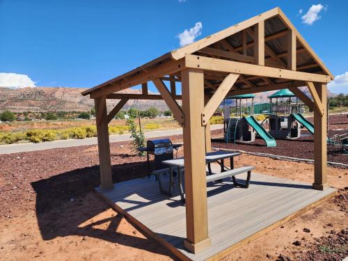 einen hölzernen Pavillon mit einem Picknicktisch und einem Spielplatz in der Unterkunft Charming Tiny Home with private deck and bbq in Apple Valley
