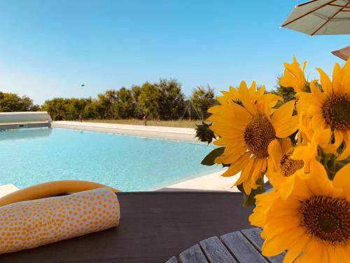 un vase de tournesols assis sur une table près de la piscine dans l'établissement Le Buscagneau, à Béraut