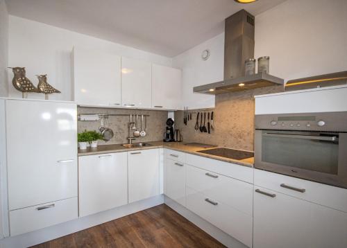 a white kitchen with white cabinets and a stove at Studio Noordzee in Egmond aan Zee