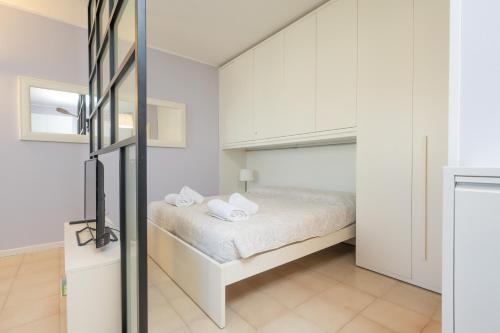um quarto com uma cama com paredes brancas em Casa Lugana 9 - monolocale con piscina fronte lago em Sirmione