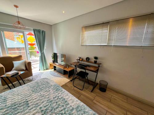 Entire Studio Apartment in Maboneng في جوهانسبرغ: غرفة نوم فيها سرير ومكتب