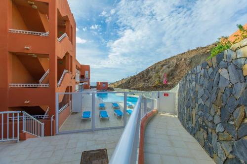 a house with a swimming pool and a stone wall at Estrella Home - Appartamento Vista Oceano in Costa Calma