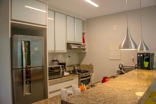 a kitchen with white cabinets and a stainless steel refrigerator at Imbassaí Solaris Village 2 quartos in Imbassai
