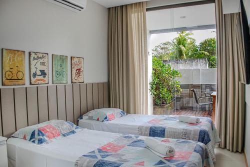 two beds in a room with a window at Imbassaí Solaris Village 2 quartos in Imbassai