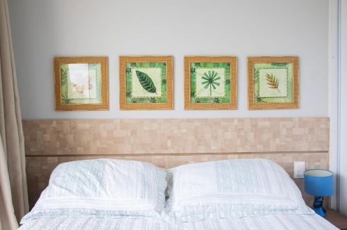 a bedroom with four pictures on the wall above a bed at Imbassaí Solaris Village 2 quartos in Imbassai