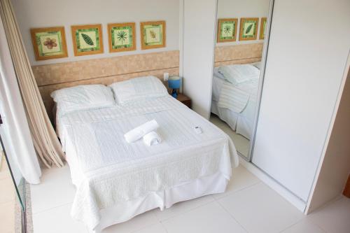 a bedroom with a white bed and a mirror at Imbassaí Solaris Village 2 quartos in Imbassai