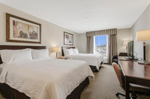 a hotel room with two beds and a desk at Holiday Inn & Suites Lloydminster, an IHG Hotel in Lloydminster