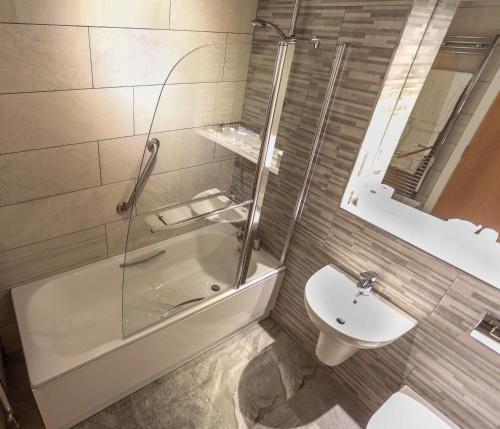y baño con ducha, aseo y lavamanos. en Ballymac Hotel, en Stonyford