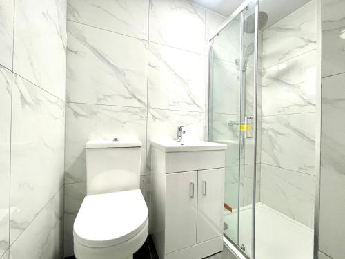 a white bathroom with a toilet and a shower at Kings Cross Guest House in London