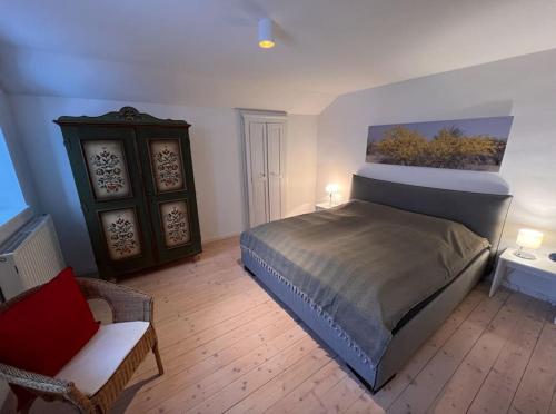 1 dormitorio con 1 cama y 1 silla en una habitación en NEU - traumhafte Ferienwohnung mit Bergblick en Lenggries