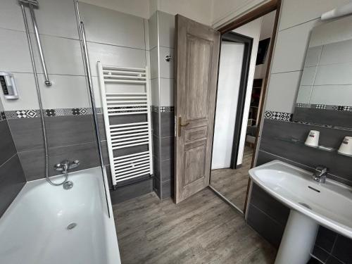 La salle de bains est pourvue d'une baignoire, d'un lavabo et d'un miroir. dans l'établissement Le Richelieu Bacchus, à Fontainebleau